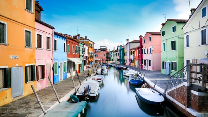 boats on canal between houses during daytime